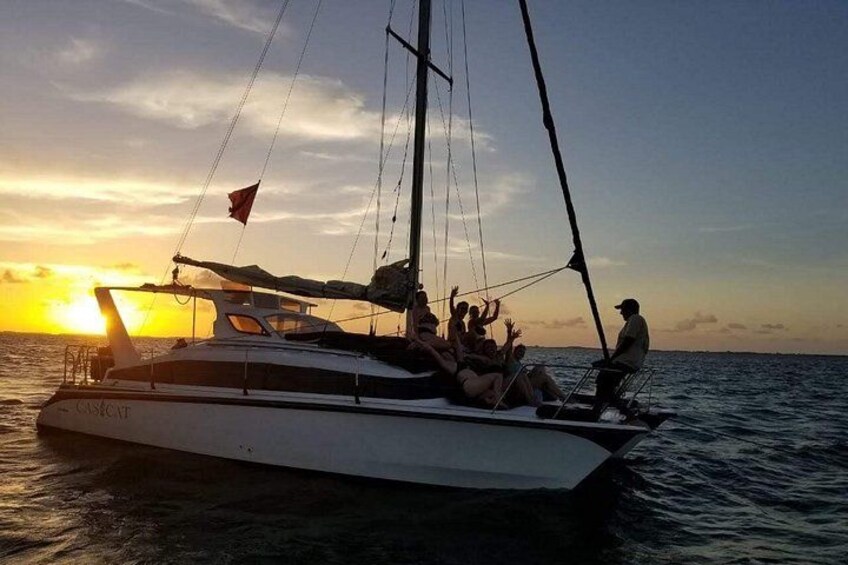 A sailboat with people on board during sunset. 2