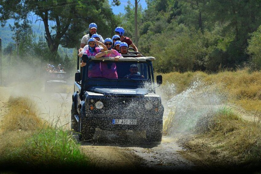 A vehicle driving through a muddy path with people on board. 3