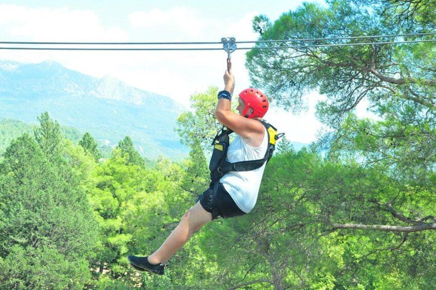 A person zip-lining through a forested area with mountains in the background. 4
