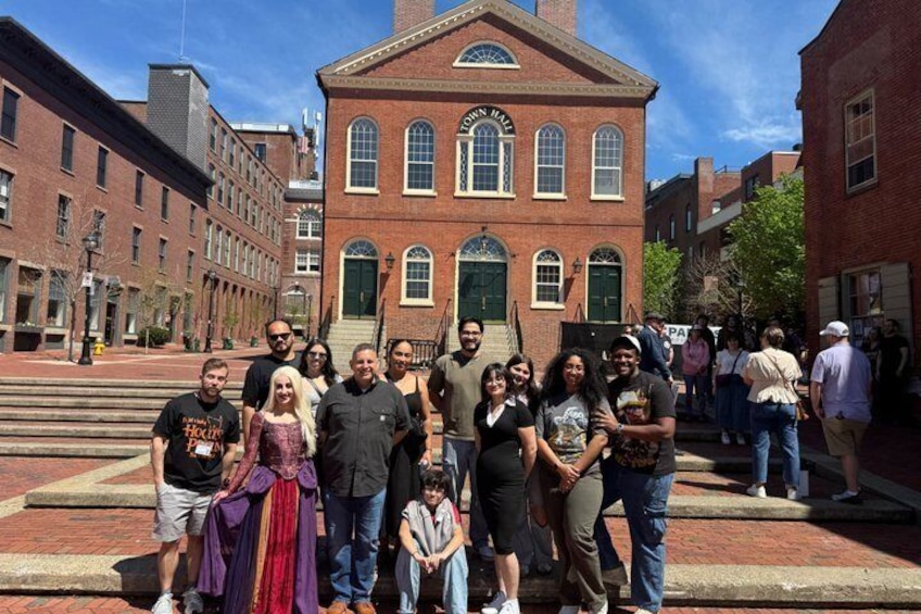A group of people posing in front of a historic building with a green door and arched windows. 3