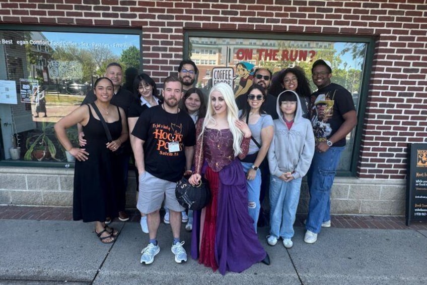 A group of people posing in front of a brick building with a sign that reads 'ON THE RUN?' 5