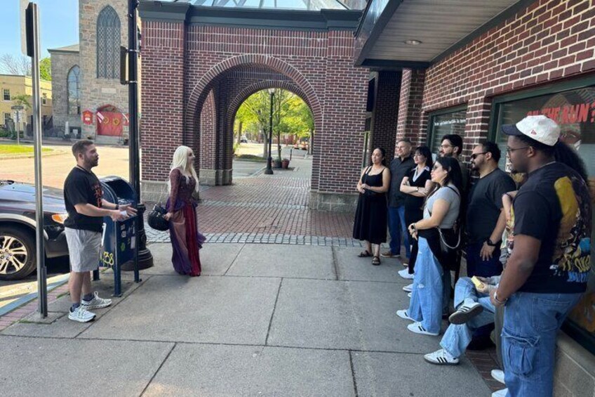 A group of people standing outside a brick building with an arched entrance. 4