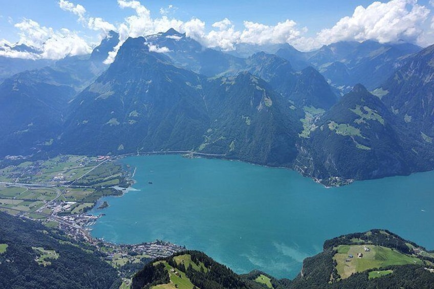 A mountainous landscape with a large turquoise lake surrounded by lush greenery and a small settlement. 5