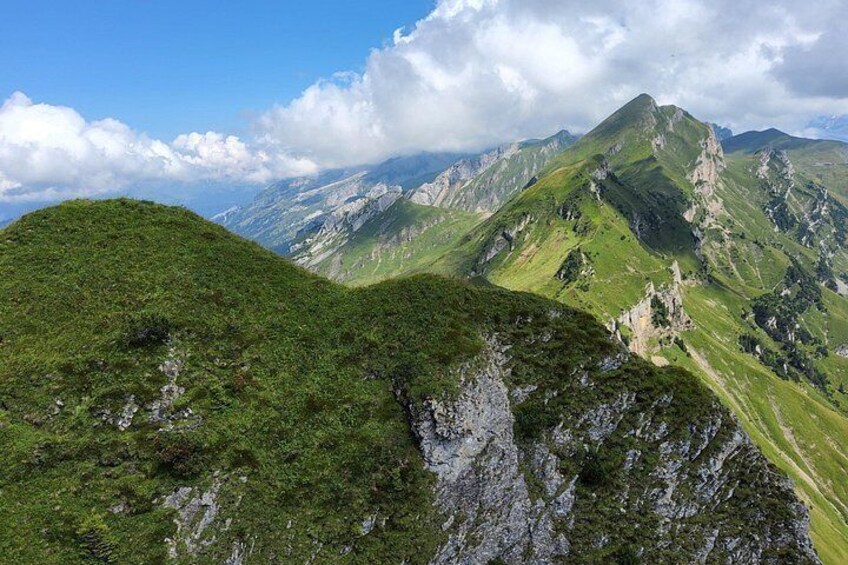 A mountainous landscape with green slopes and rocky outcrops. 3