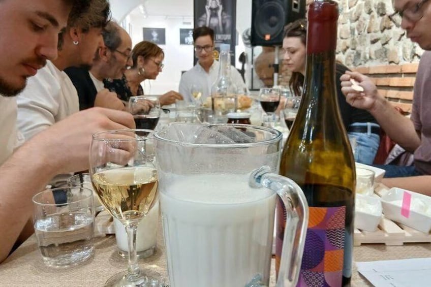 A group of people seated at a table with a wine bottle, glasses, and a pitcher. 4