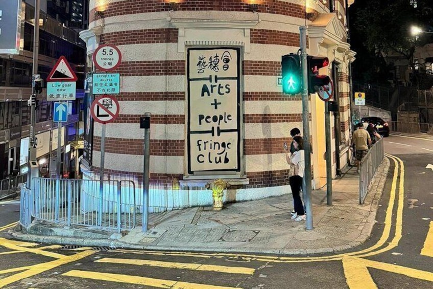 A street corner with a building featuring a large signboard, traffic lights, and a pedestrian crossing. 2