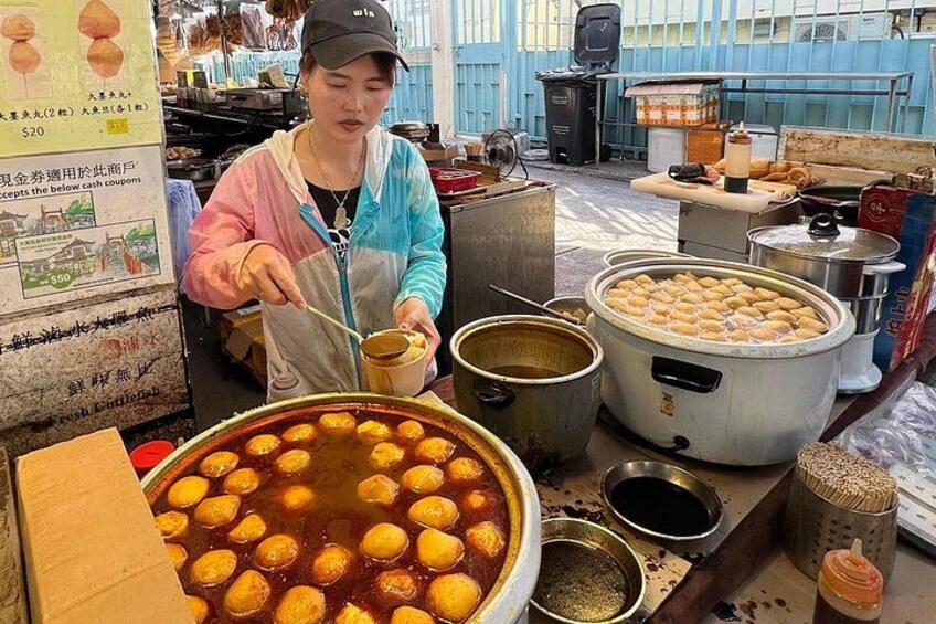 Un vendedor ambulante de comida preparando alimentos, con ollas y recipientes grandes llenos de comida a la vista. 3