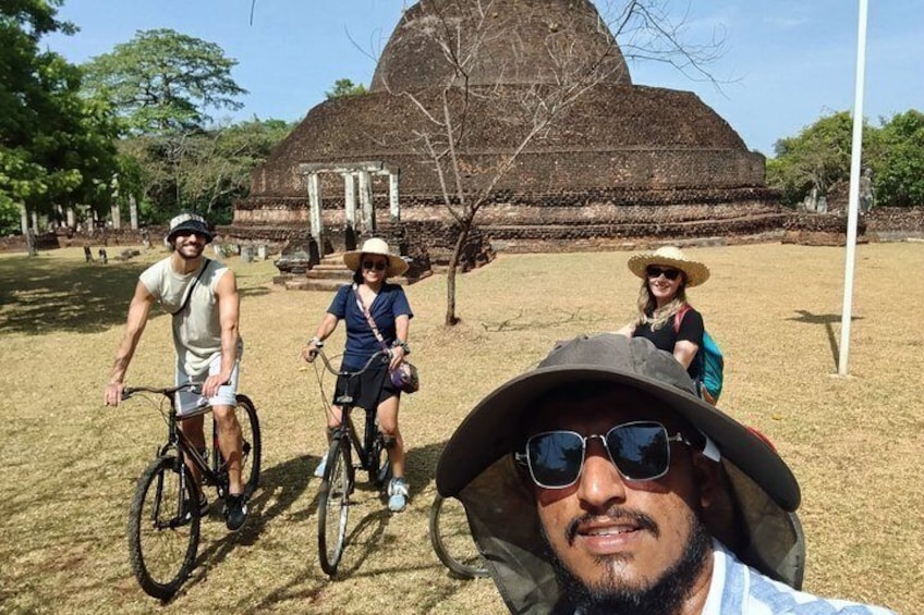A group of people on bicycles, a large ancient structure, and a clear sky. 3