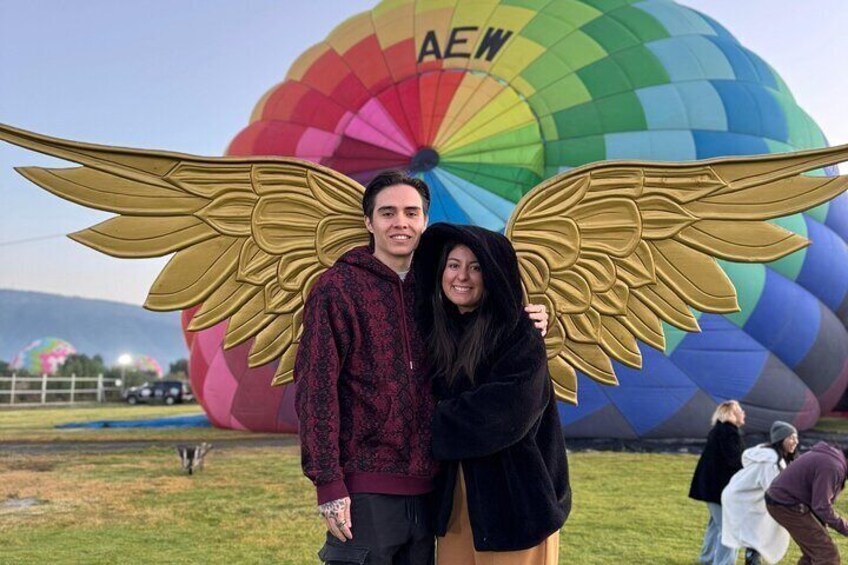A person with angel wings standing in front of a colorful hot air balloon. 2