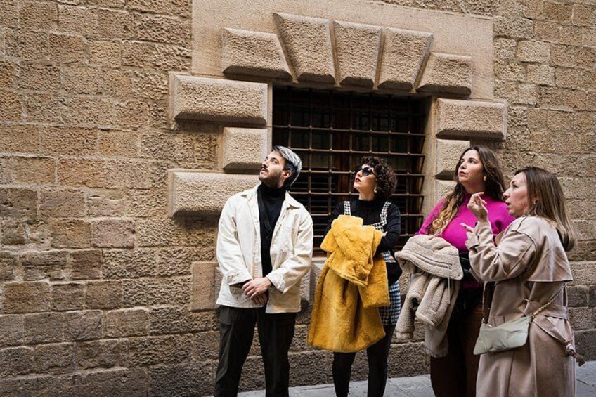 Four people standing in front of a stone building with a window and a door. 3
