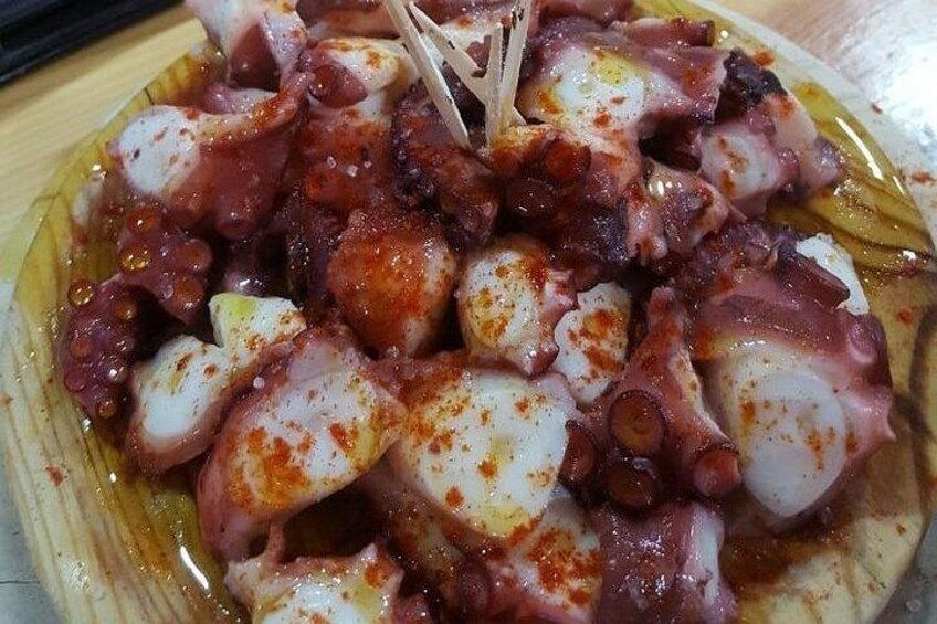 A plate of octopus with a reddish seasoning, served on a yellow plate. 2