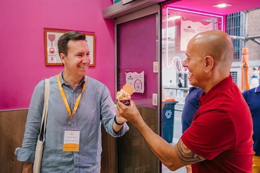 Two people in a pink room, one holding a sandwich. 3