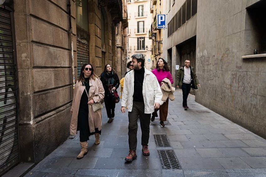 A group of people walking on a narrow urban street with buildings on either side. 5