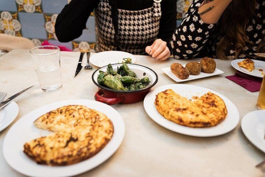 A dining table with plates of food, a glass of water, and cutlery. 4