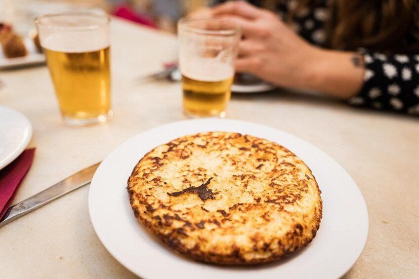 A round, golden-brown pancake on a white plate, with a fork beside it. 1
