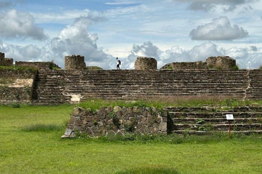 Ancient ruins with stone steps and walls, a grassy field, and a partly cloudy sky. 3