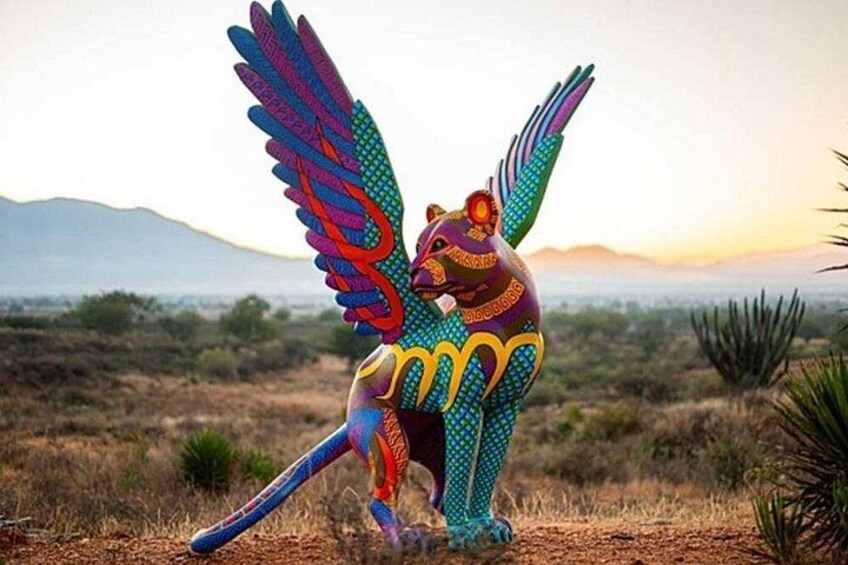 A colorful sculpture of a bird with outstretched wings in a desert landscape. 3