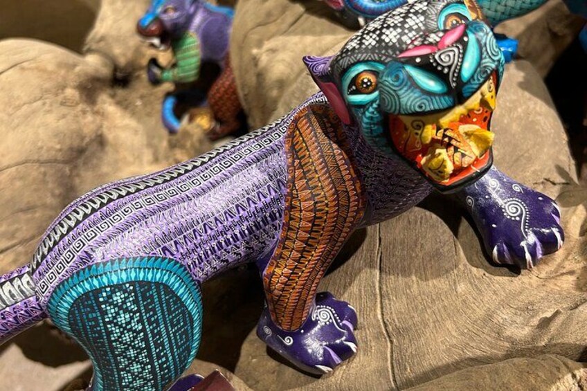 A colorful, intricately designed toy dinosaur on a rock. 2