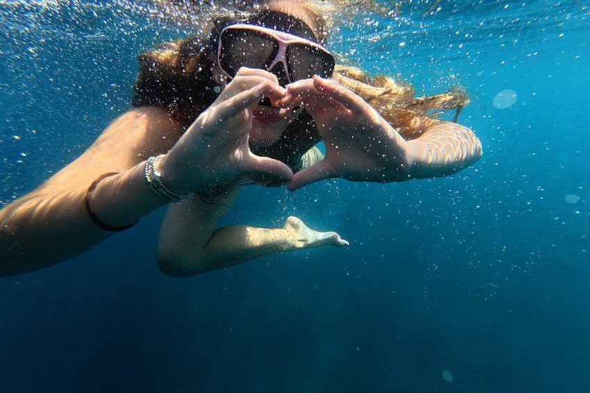 A person underwater making a heart shape with their hands. 2