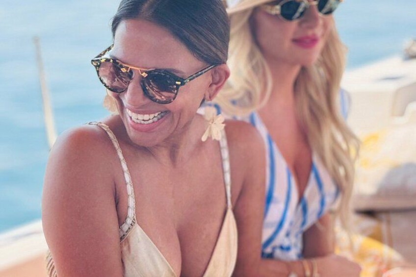Two people on a boat, one wearing a white swimsuit and the other in a striped swimsuit. 5
