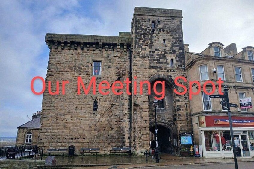 A historic stone building with a tower, a shop with a sign, and a bench. 3