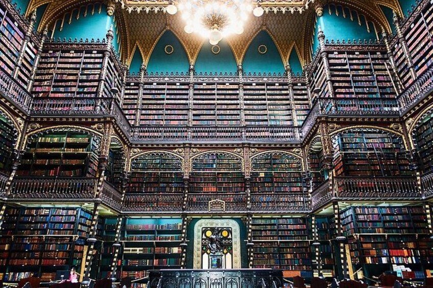 Een statige bibliotheek met versierde architectuur, meerdere boekenkasten en een centraal decoratief element. 1