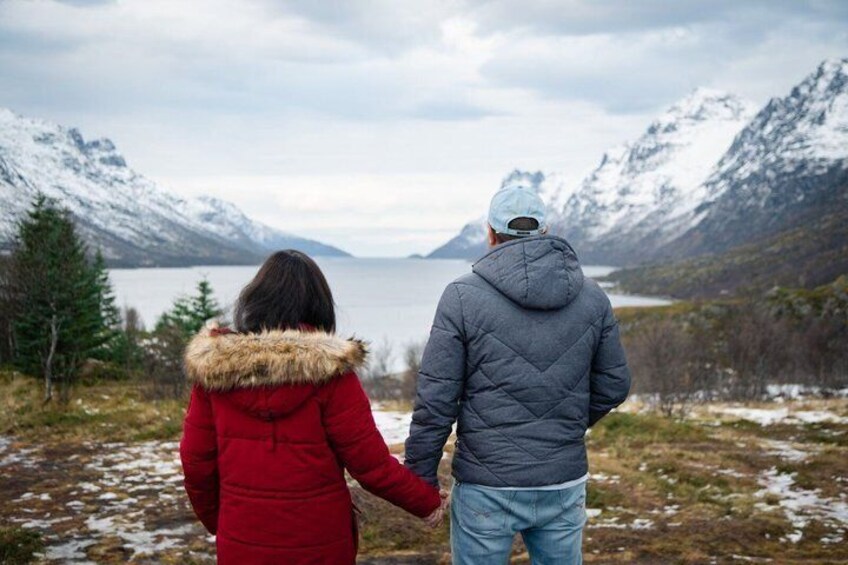 A couple holding hands, overlooking a lake with mountains in the background. 5