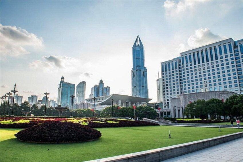 A cityscape with modern buildings, a park with green lawns, and a clear sky. 4