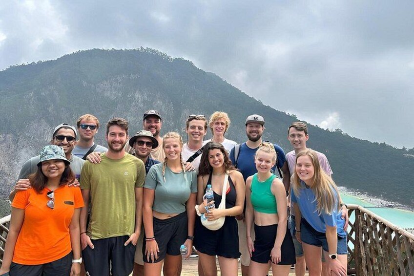 A group of people standing on a wooden deck with a mountainous landscape in the background. 1