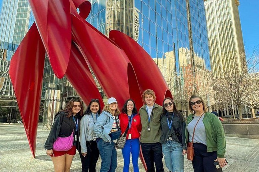 A group of people standing in front of a large red sculpture. 5