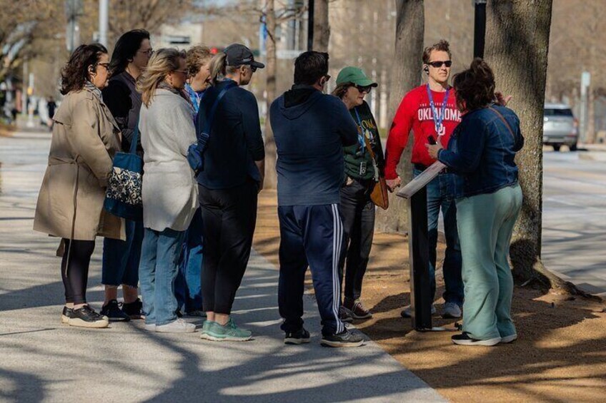 A group of people standing on a sidewalk, engaged in a discussion. 2
