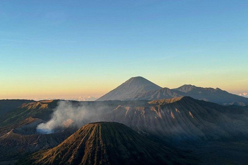 A volcanic landscape with a prominent mountain and visible smoke. 4