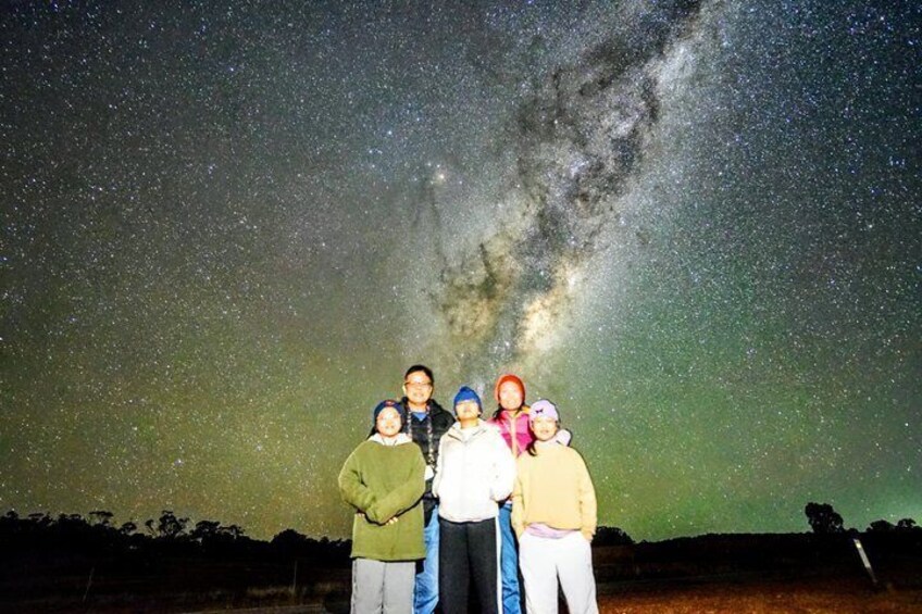 A group of people standing under a starry night sky with the Milky Way visible. 2