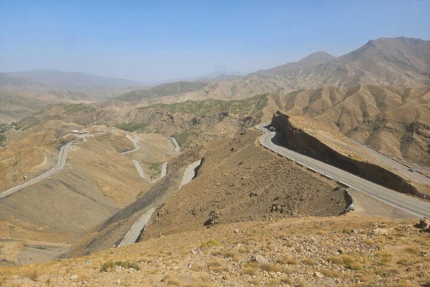A winding mountain road with rocky terrain and distant hills. 3