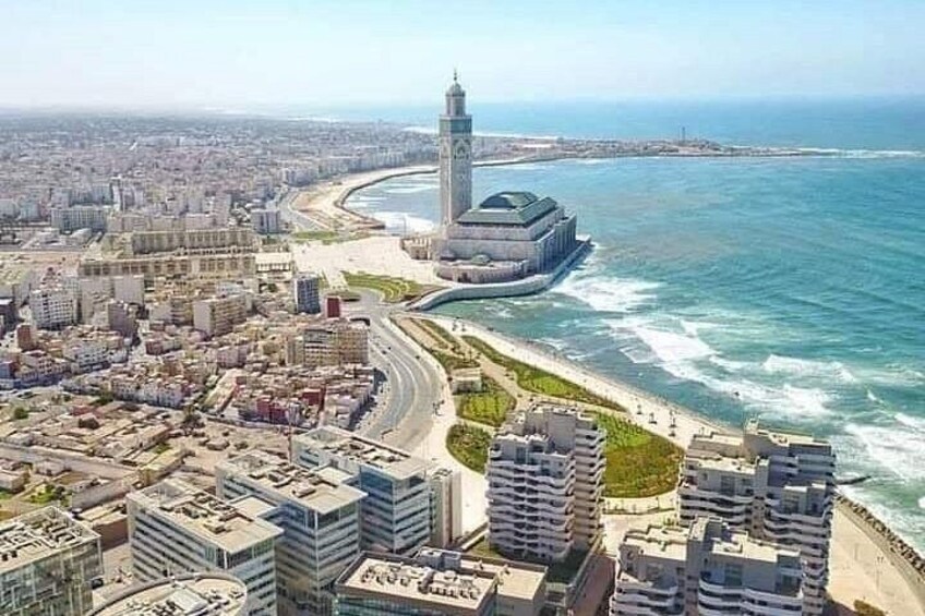 A coastal cityscape with a prominent tower, a beach, and dense urban development. 1