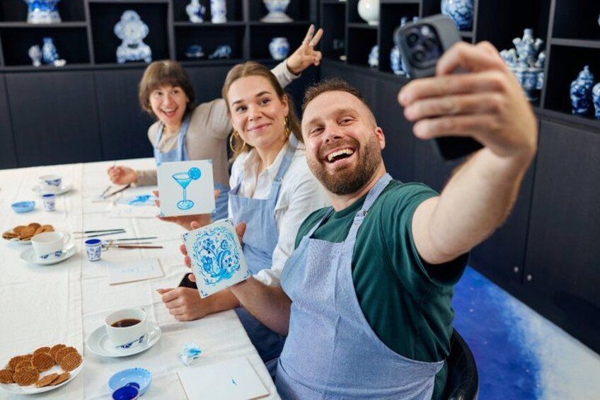 People taking a selfie at a table with blue and white ceramic items. 3