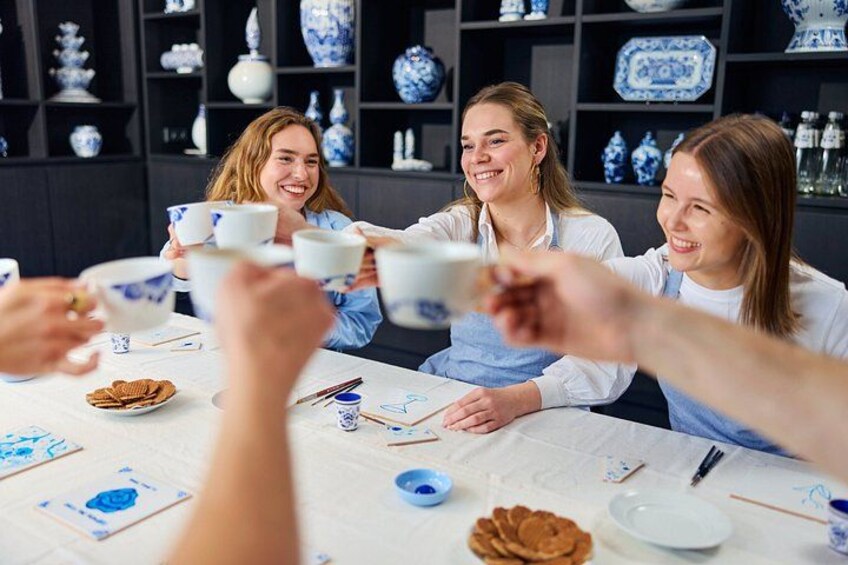 A group of people at a table with blue and white ceramic cups, surrounded by bowls and plates. 2