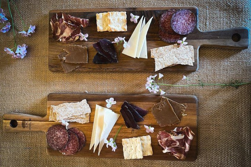Two wooden boards with various cheeses, meats, and crackers. 3