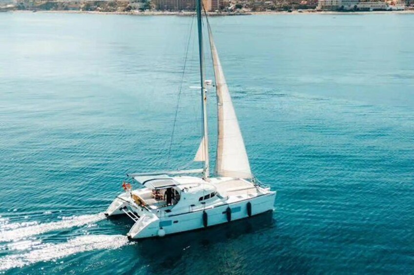 A white sailboat with a single mast sailing on a calm sea. 2