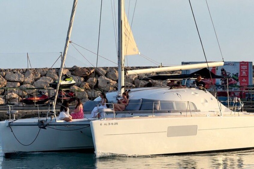 A sailboat docked at a marina with a rocky breakwater in the background. 3