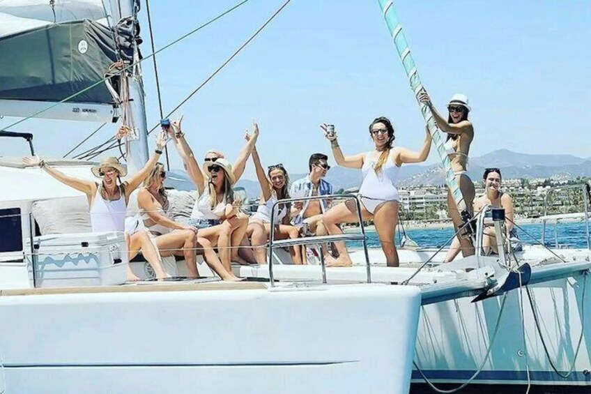 A group of people on a sailboat with a clear sky and distant land in the background. 4