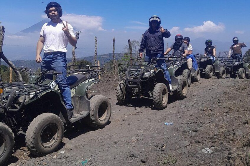 A group of people on quad bikes on a dirt path with a mountainous background. 2