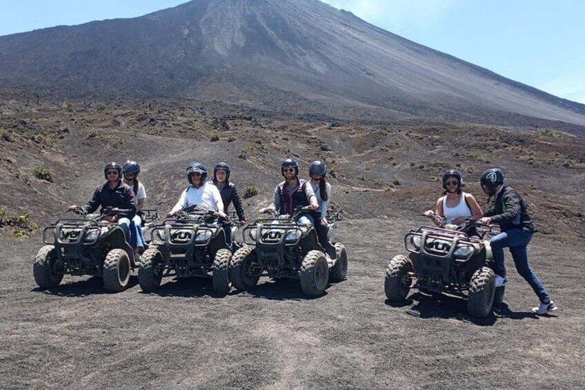 A group of people on ATVs in a barren landscape with a volcano in the background. 4