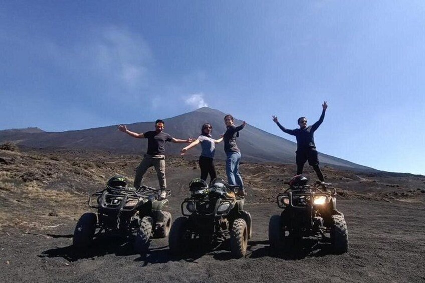 Four people on all-terrain vehicles with a volcano in the background. 1