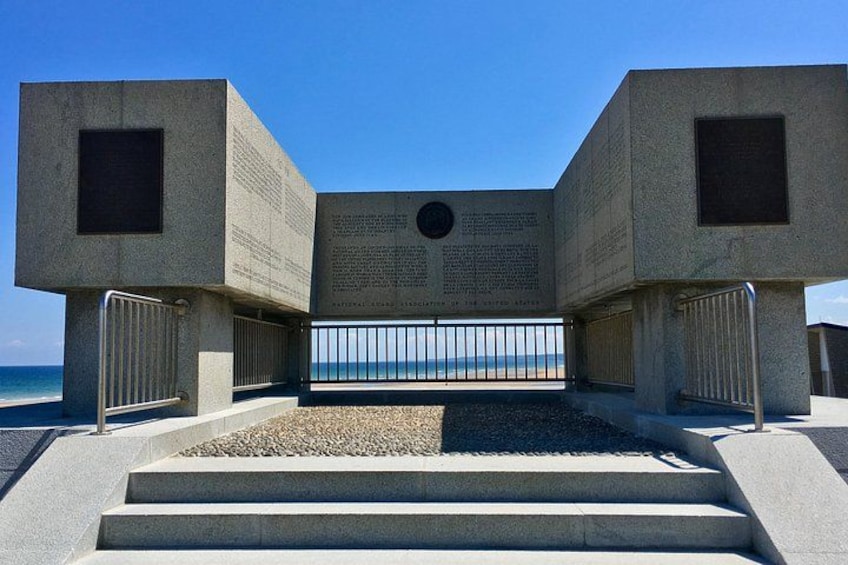 A concrete memorial with inscriptions and a view of the ocean. 4