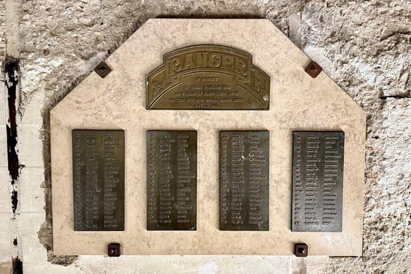 A stone plaque with inscriptions and a metal sign above it. 5