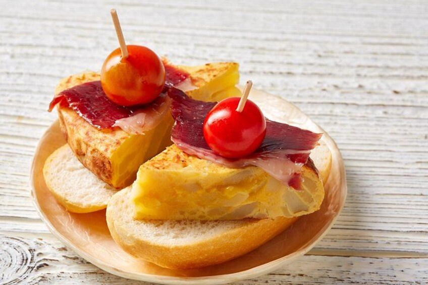 A plate with a slice of bread topped with ham and a cherry. 5