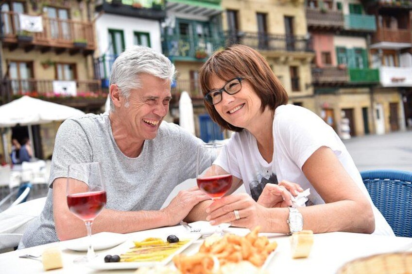 Two people sitting at an outdoor table with food and drinks. 4