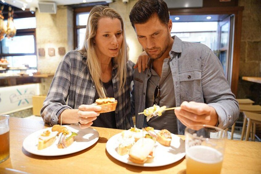 Two people sitting at a table with plates of food and a glass of beer. 2