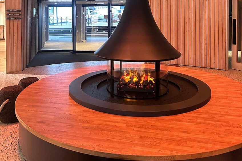 A round wooden table with a central fire feature. 3